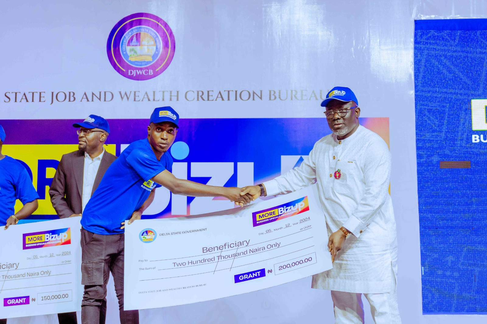 Delta State Governor, Rt. Hon. Sheriff Oborevwori (right) presenting a dummy cheque to one of the beneficiaries of Delta State Job and Wealth Creation More Bizup Grant Disbursement in Asaba on Thursday, December 5, 2024, in Asaba.